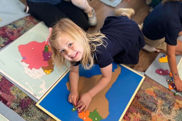 Children working with Montessori puzzle maps and geography materials