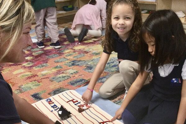 Teacher working with children on Montessori moveable alphabet literacy activity